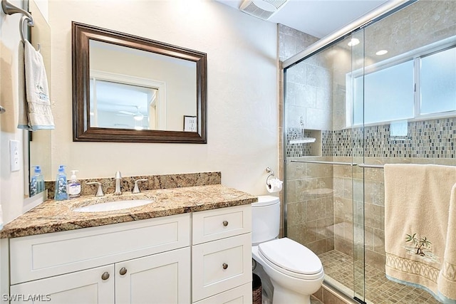 bathroom featuring vanity, toilet, and a shower with shower door