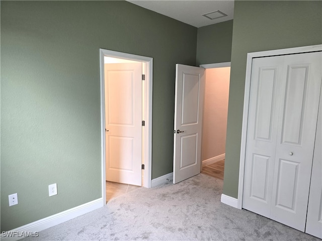 unfurnished bedroom featuring light carpet and a closet