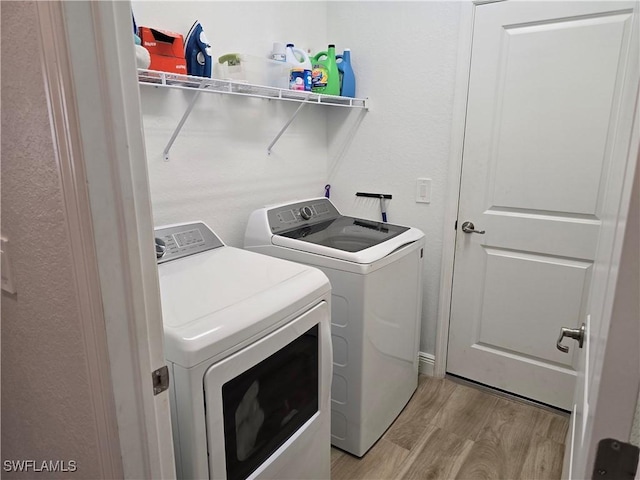 washroom with light hardwood / wood-style floors and separate washer and dryer