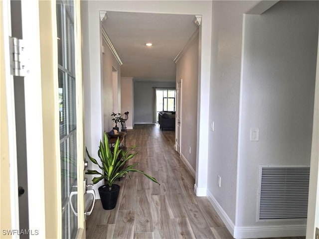 hall with ornamental molding and light wood-type flooring