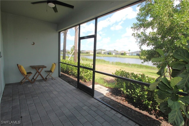 unfurnished sunroom with ceiling fan and a water view