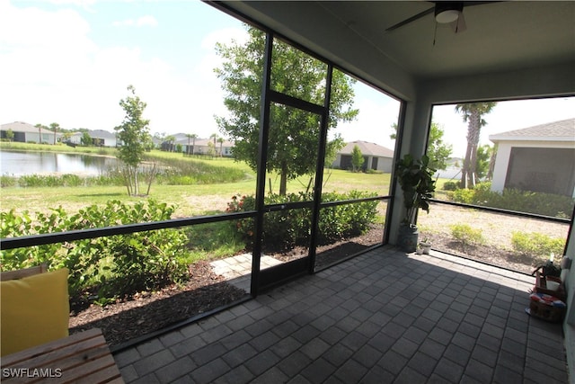 unfurnished sunroom featuring ceiling fan and a water view