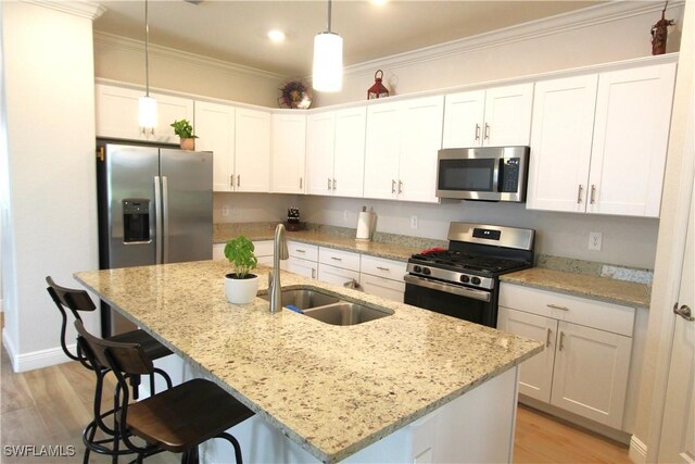 kitchen featuring appliances with stainless steel finishes, light hardwood / wood-style flooring, sink, white cabinets, and hanging light fixtures