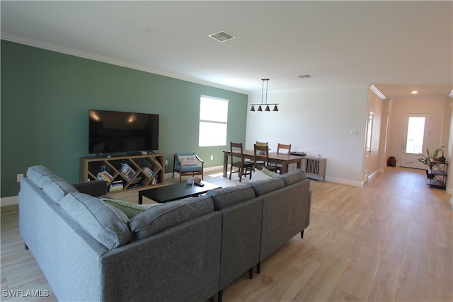 living room with light hardwood / wood-style flooring, a healthy amount of sunlight, and ornamental molding