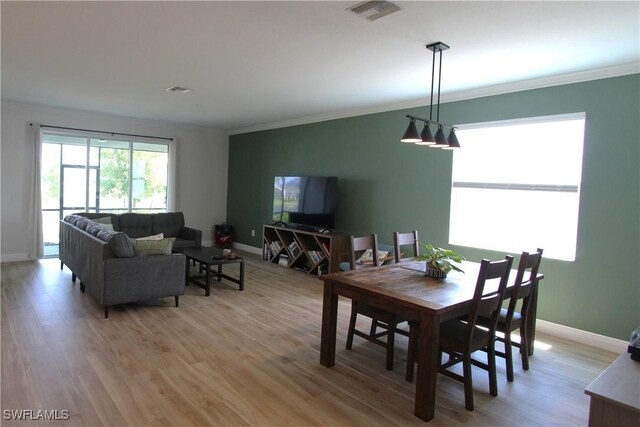 dining space featuring ornamental molding and light wood-type flooring