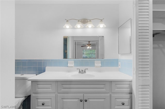 bathroom featuring ceiling fan, vanity, tile walls, and toilet