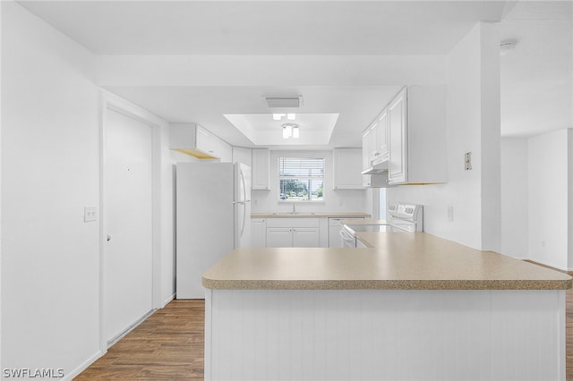 kitchen with kitchen peninsula, white cabinets, light hardwood / wood-style floors, and white appliances