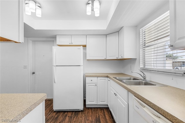 kitchen with sink, dark wood-type flooring, a raised ceiling, white appliances, and white cabinets