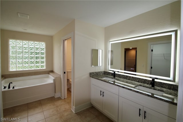 bathroom featuring double vanity, tile patterned floors, a tub to relax in, and toilet