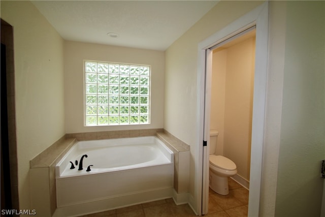 bathroom with tile patterned floors, toilet, and a tub to relax in