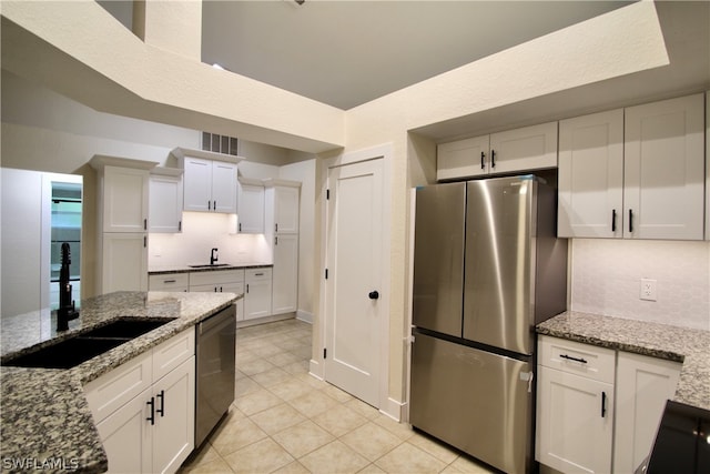 kitchen with white cabinetry, backsplash, stainless steel appliances, light stone countertops, and sink