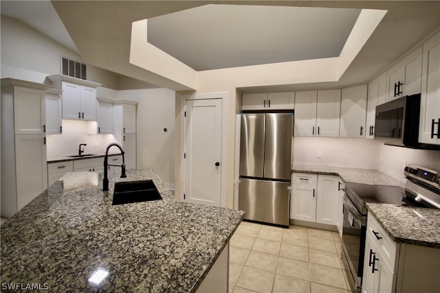 kitchen with sink, appliances with stainless steel finishes, white cabinets, and a raised ceiling