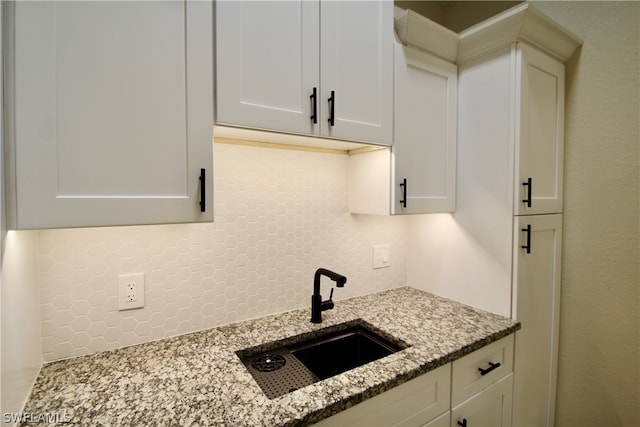 kitchen featuring white cabinetry, stone counters, tasteful backsplash, and sink