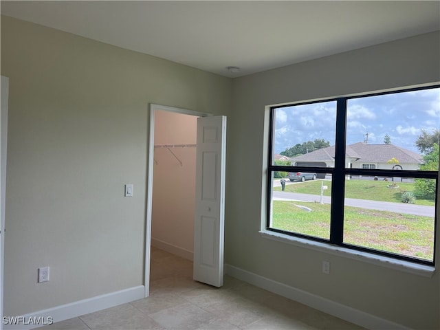 unfurnished bedroom with light tile patterned floors, a spacious closet, and a closet