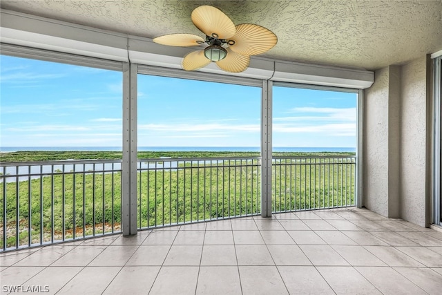 unfurnished sunroom featuring a water view and ceiling fan