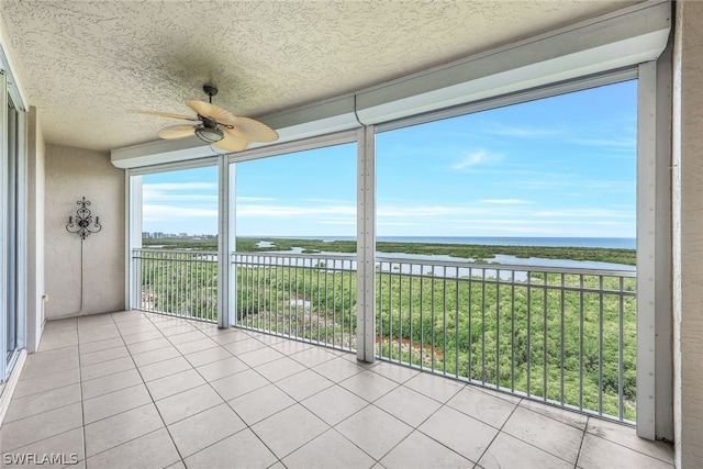 unfurnished sunroom featuring a water view and ceiling fan