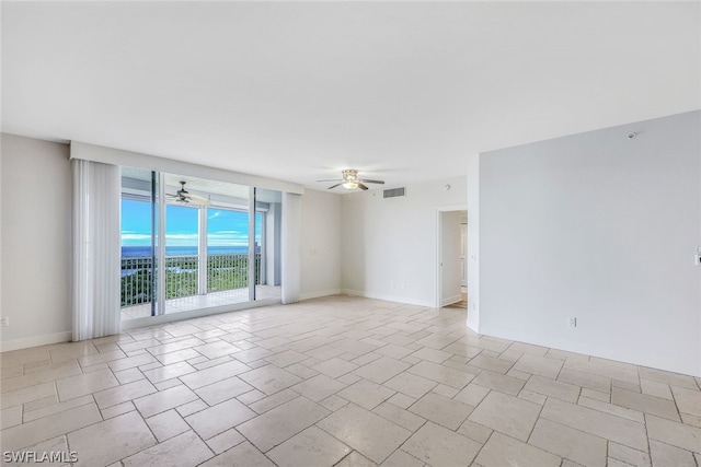 tiled empty room featuring expansive windows and ceiling fan