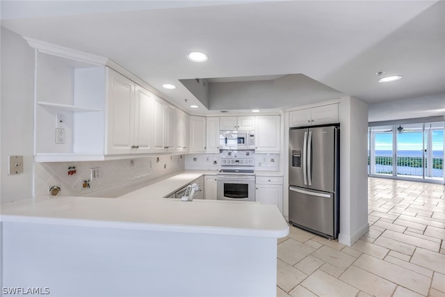 kitchen with white cabinetry, light tile patterned floors, decorative backsplash, white appliances, and kitchen peninsula