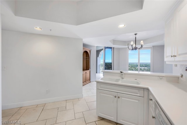 kitchen featuring hanging light fixtures, sink, a raised ceiling, white cabinets, and a chandelier