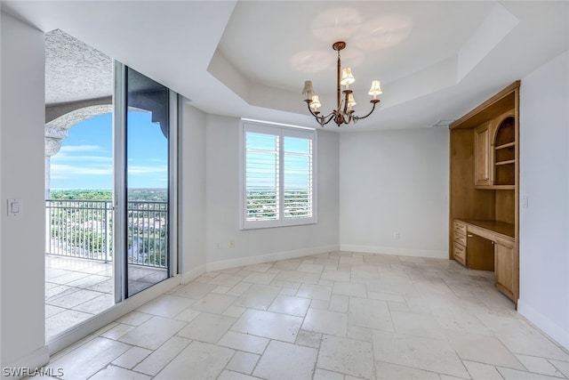 spare room featuring plenty of natural light, a tray ceiling, and a notable chandelier