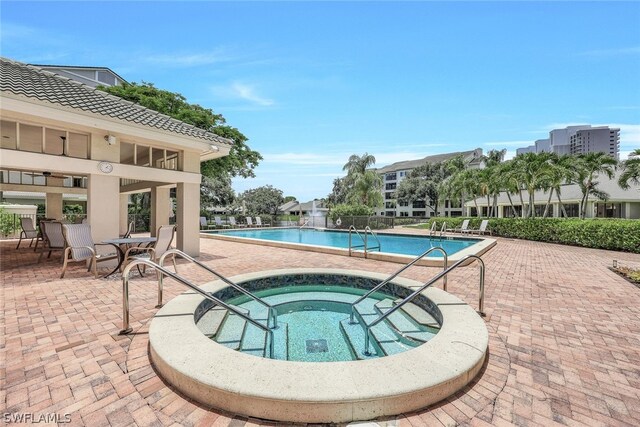 view of swimming pool featuring a patio and a hot tub