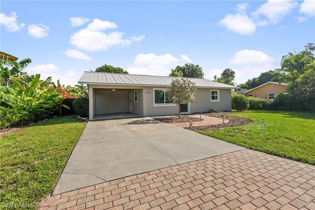 single story home featuring stucco siding, metal roof, decorative driveway, and a front yard