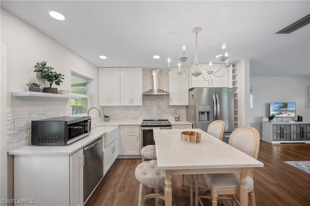 kitchen with stainless steel appliances, white cabinets, backsplash, dark wood-type flooring, and wall chimney exhaust hood