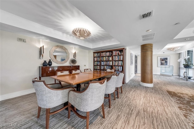 dining room with baseboards, a tray ceiling, visible vents, and ornate columns