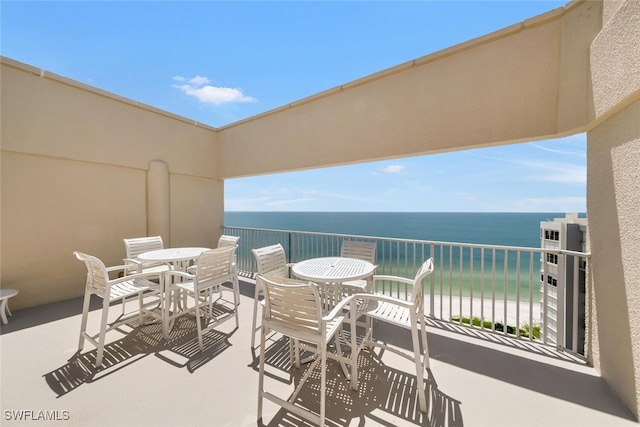 balcony featuring a water view, outdoor dining area, and a view of the beach