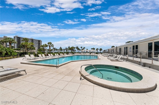 pool with a patio area and a hot tub