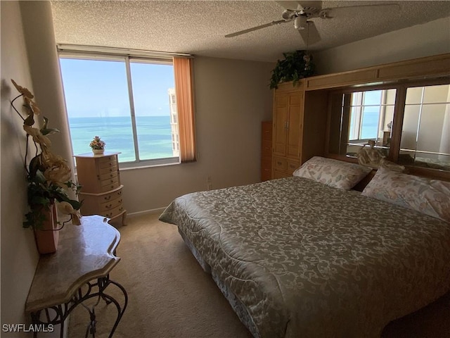 bedroom with a ceiling fan, carpet flooring, and a textured ceiling