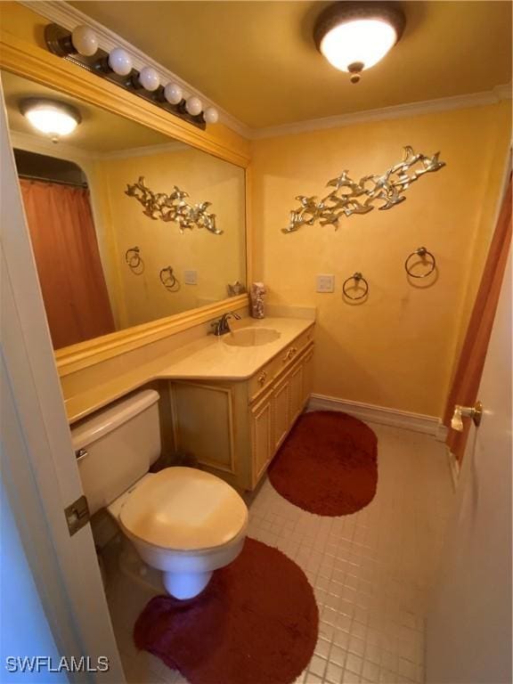 bathroom featuring toilet, ornamental molding, vanity, tile patterned flooring, and baseboards