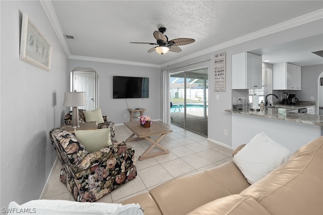 tiled living room with a textured ceiling, ceiling fan, ornamental molding, and sink