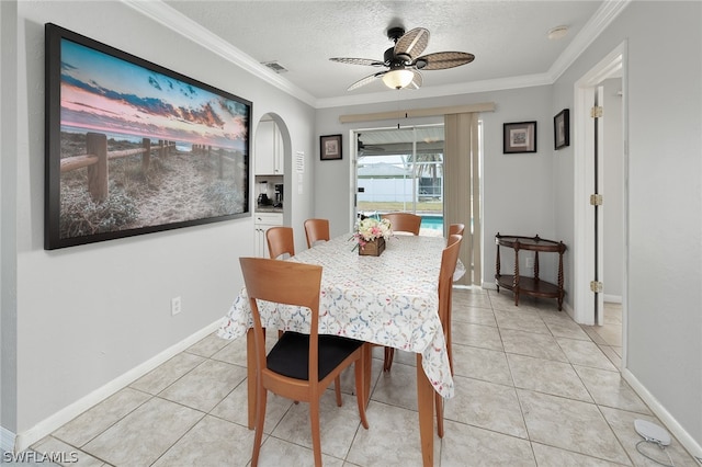 tiled dining space featuring ceiling fan, crown molding, and a textured ceiling