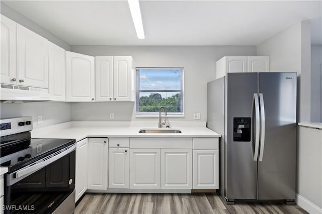 kitchen featuring white cabinetry, sink, range hood, light hardwood / wood-style floors, and appliances with stainless steel finishes