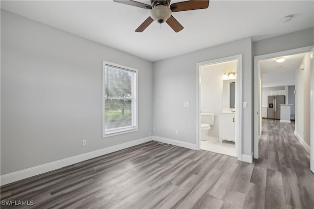 unfurnished bedroom with hardwood / wood-style floors, ensuite bathroom, stainless steel fridge, and ceiling fan