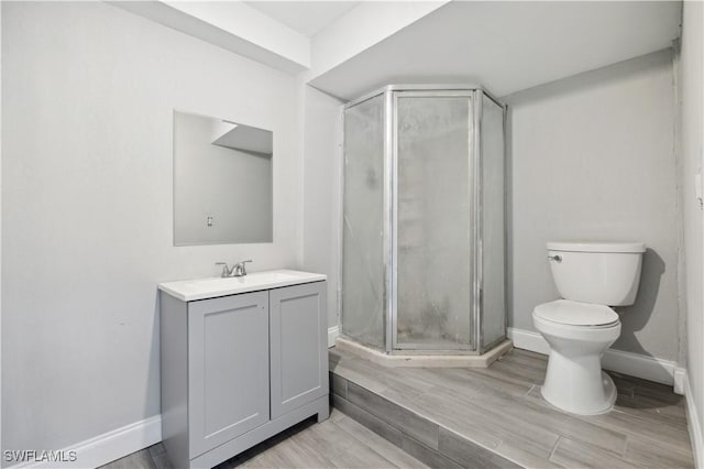 bathroom with toilet, vanity, wood-type flooring, and walk in shower