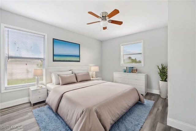 bedroom with multiple windows, ceiling fan, and light hardwood / wood-style flooring