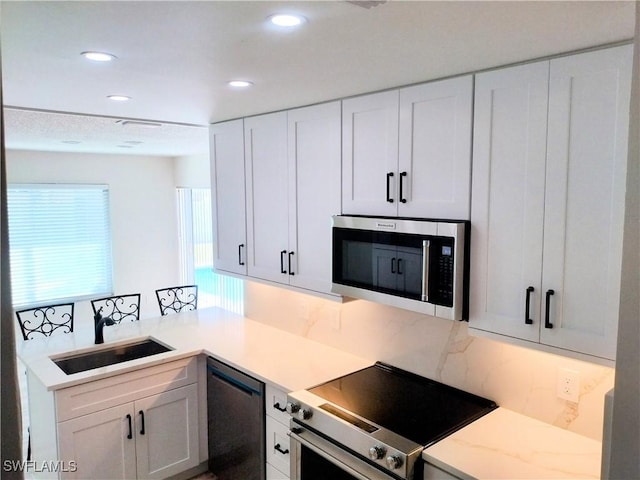 kitchen featuring white cabinetry, sink, appliances with stainless steel finishes, and tasteful backsplash