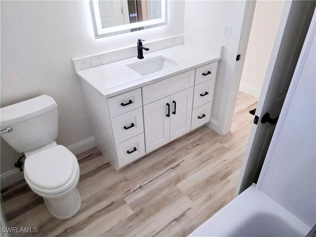 bathroom with hardwood / wood-style floors, vanity, and toilet