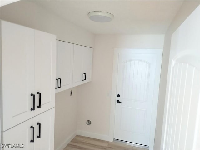 clothes washing area with electric dryer hookup, light hardwood / wood-style flooring, and cabinets