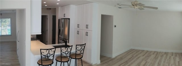 kitchen with ceiling fan, white cabinetry, light wood-type flooring, and stainless steel fridge with ice dispenser