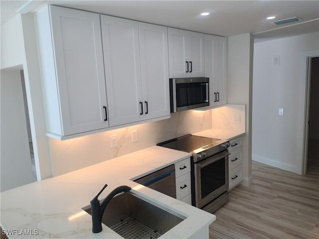 kitchen featuring white cabinets, light wood-type flooring, sink, and appliances with stainless steel finishes