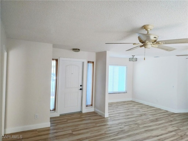 entryway with ceiling fan, light hardwood / wood-style floors, and a textured ceiling