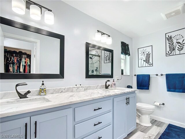 15711 Anderson Ln, Fort Myers, FL 33912 - bathroom featuring a shower, toilet, double vanity, baseboards, and wood finished floors
