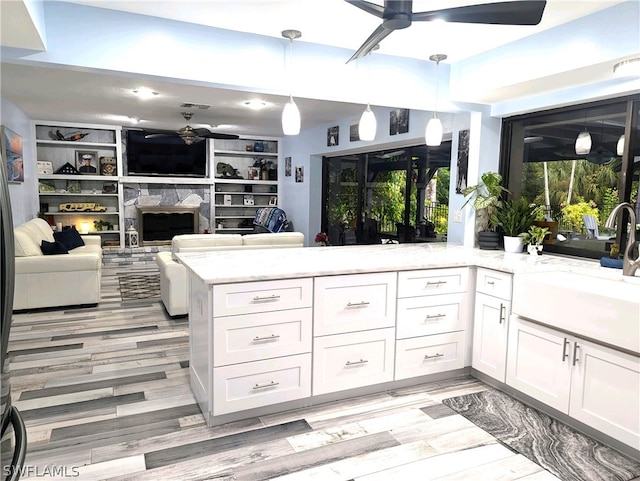 kitchen with white cabinetry, built in features, light stone counters, and decorative light fixtures