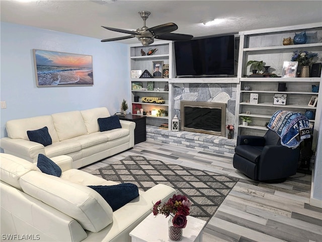 living room with ceiling fan, light wood-type flooring, and a fireplace