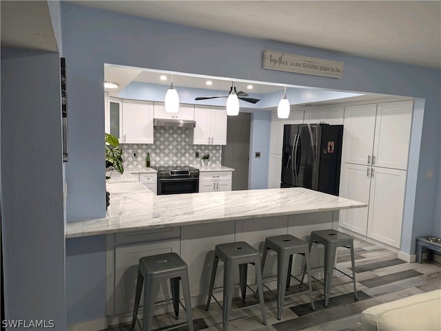 kitchen with white cabinets, a kitchen breakfast bar, kitchen peninsula, stainless steel range with electric stovetop, and black fridge with ice dispenser