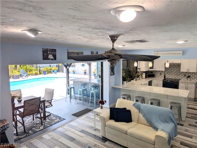 living room with sink, a textured ceiling, and light hardwood / wood-style flooring