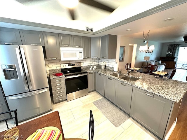 kitchen featuring stainless steel appliances, ceiling fan with notable chandelier, light stone countertops, backsplash, and kitchen peninsula